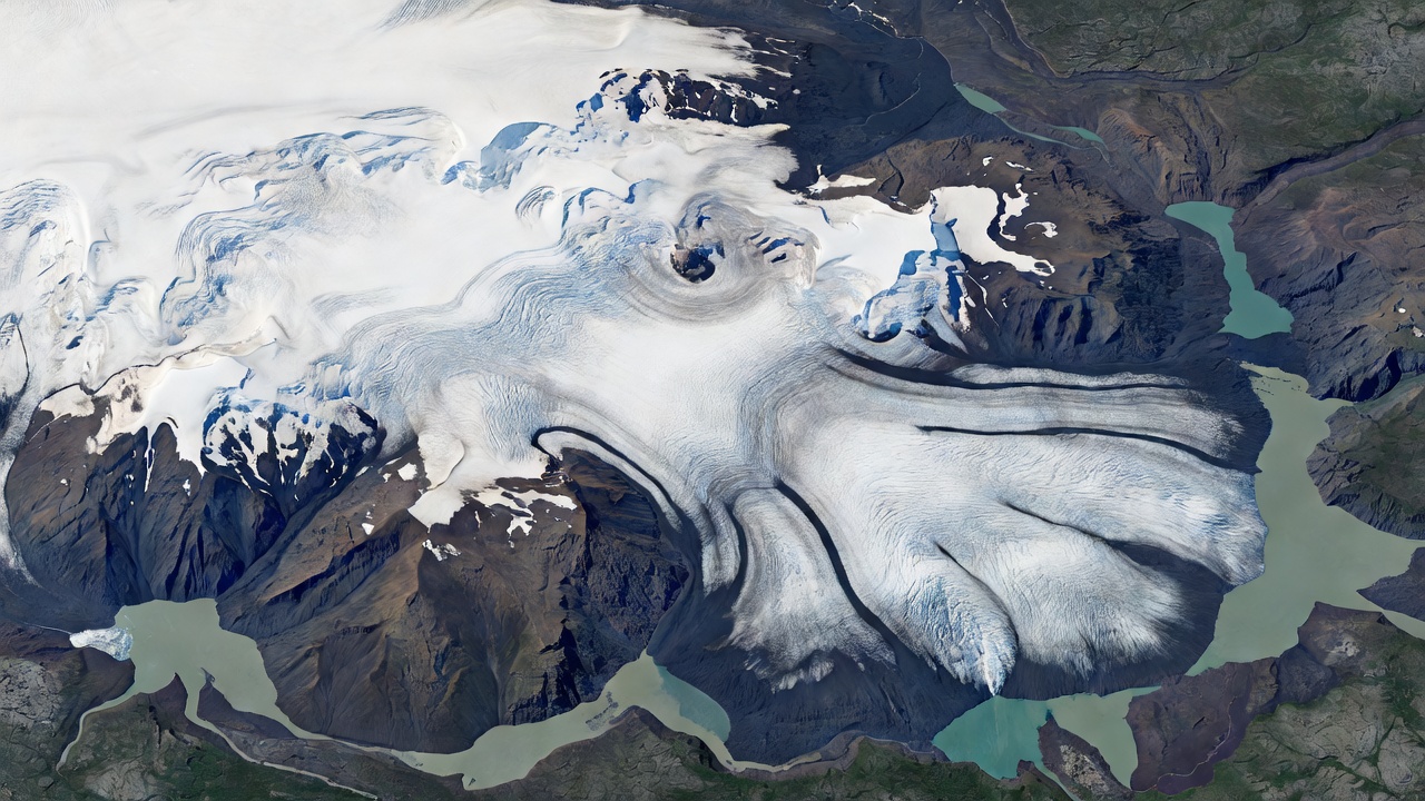 Orbital view of Vatnajokull glacier lobes in Iceland showing dark moraine loops and proglacial lagoons